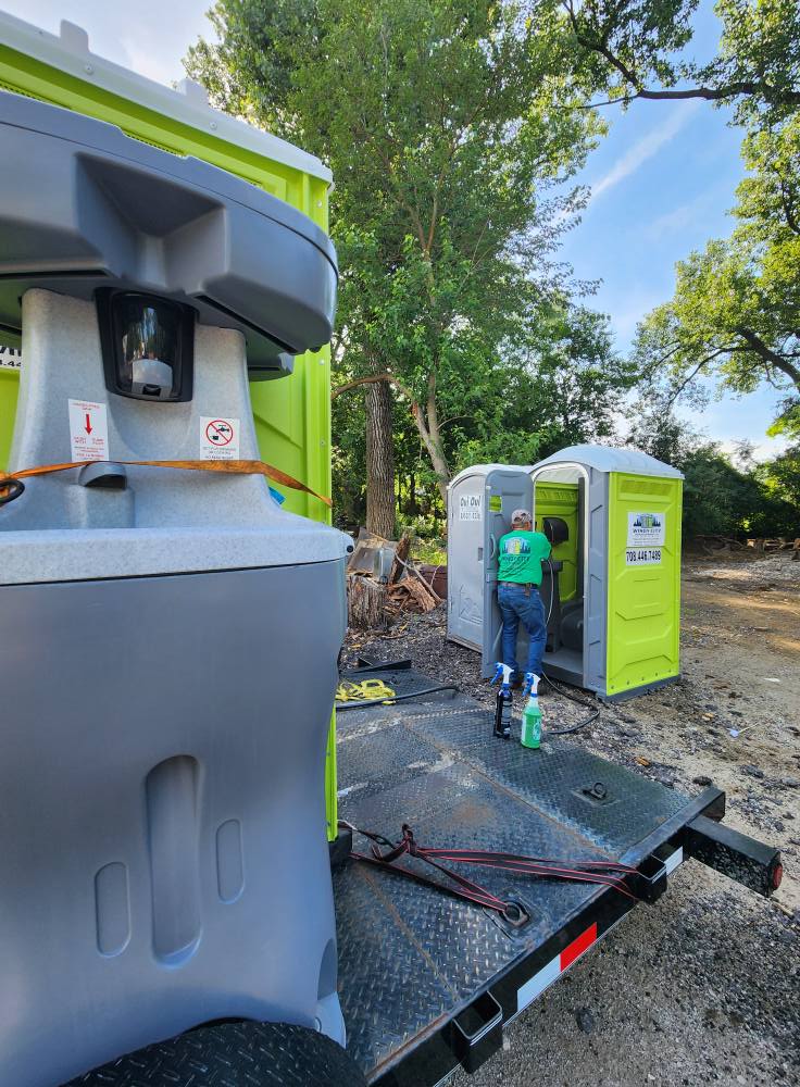 Windy City crew servicing portable restrooms on a delivery trailer